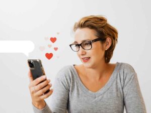 Mujer leyendo mensajes en su celular con iconos de corazones, preparándose para hablar de salud sexual con alguien que conoció en una app de citas.