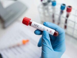 Mano con guante sosteniendo un tubo de sangre rotulado para prueba de VIH, ilustrando la importancia de los estudios médicos en la salud sexual.